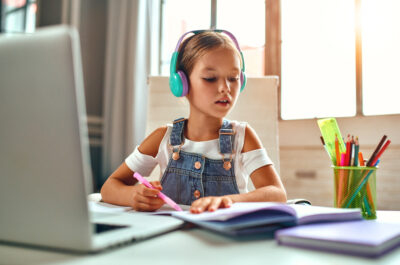 Online training. Child girl in headphones listens to a lesson on