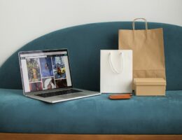 Ein Laptop und mehrere Einkaufstüten stehen auf einem Sofa.