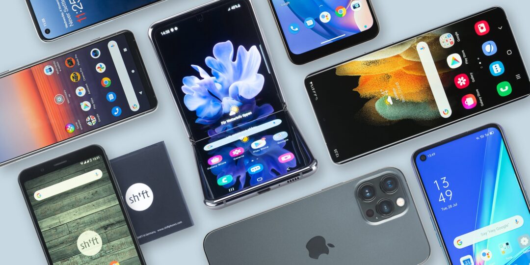 Auf einen Tisch liegen viele Smartphones in rechtwinkliger Anordnung.