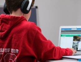 Ein Schüler sitzt mit Kopfhörern vor einem Laptop.
