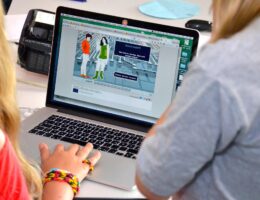 Zwei Menschen sitzen an einem Laptop.