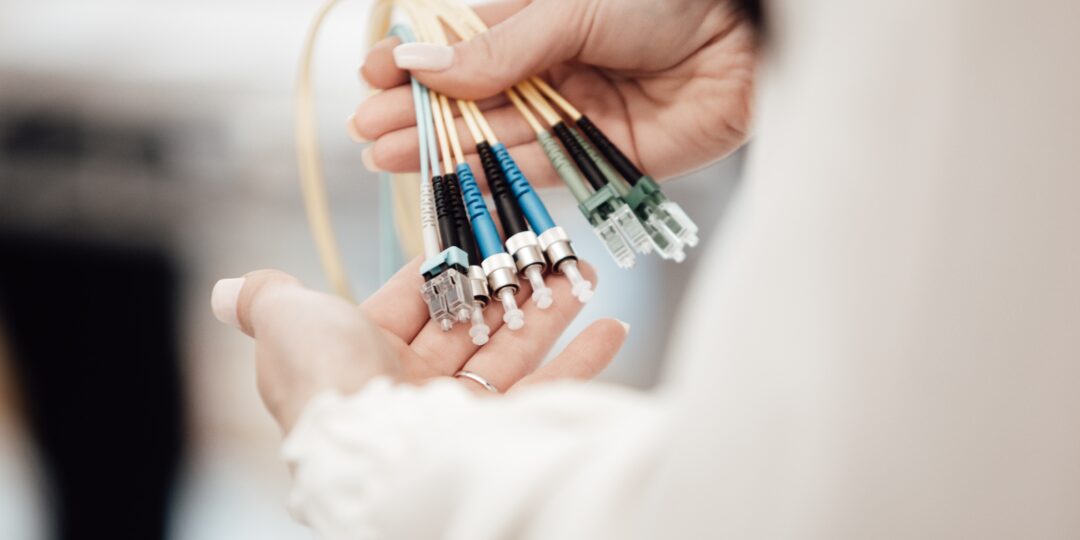 Eine Frau hält mehrere Glasfaserkabel in der Hand. Bild: Lars Kienle / Unsplash