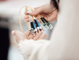 Eine Frau hält mehrere Glasfaserkabel in der Hand. Bild: Lars Kienle / Unsplash