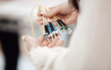 Eine Frau hält mehrere Glasfaserkabel in der Hand. Bild: Lars Kienle / Unsplash